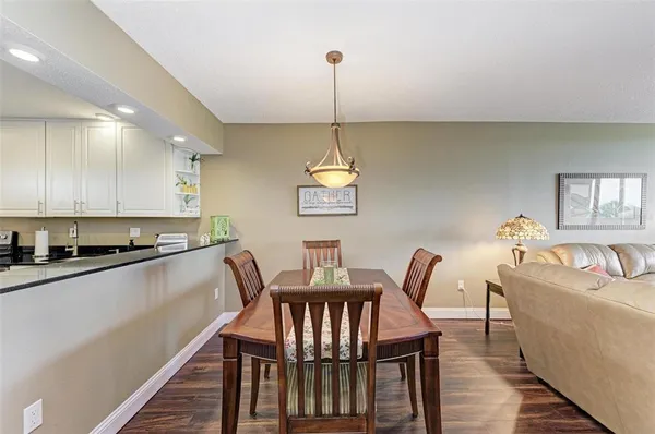 a kitchen with stainless steel appliances granite countertop a dining table chairs and a refrigerator