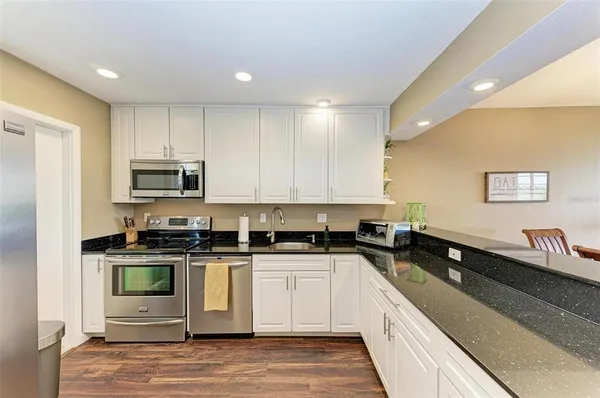 a large kitchen with stainless steel appliances granite countertop a stove a sink and a microwave