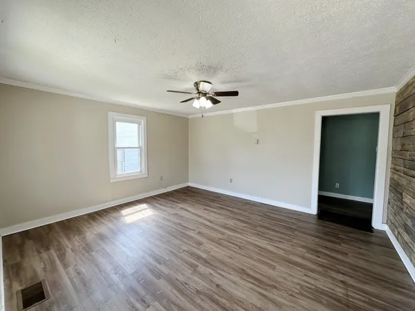 an empty room with wooden floor and windows
