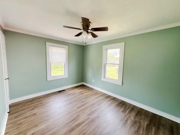 a view of an empty room with window and wooden floor