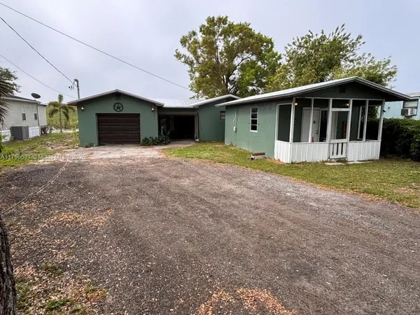 a view of a house with a yard and a large tree