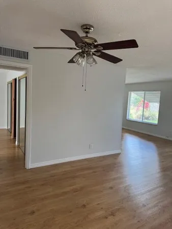 a view of a livingroom with wooden floor a ceiling fan and window