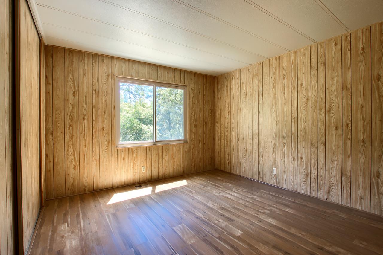2843 East Westfall Road Mariposa, CA 95338 - Photo 32 of 45 an empty room with wooden floor and windows with curtains