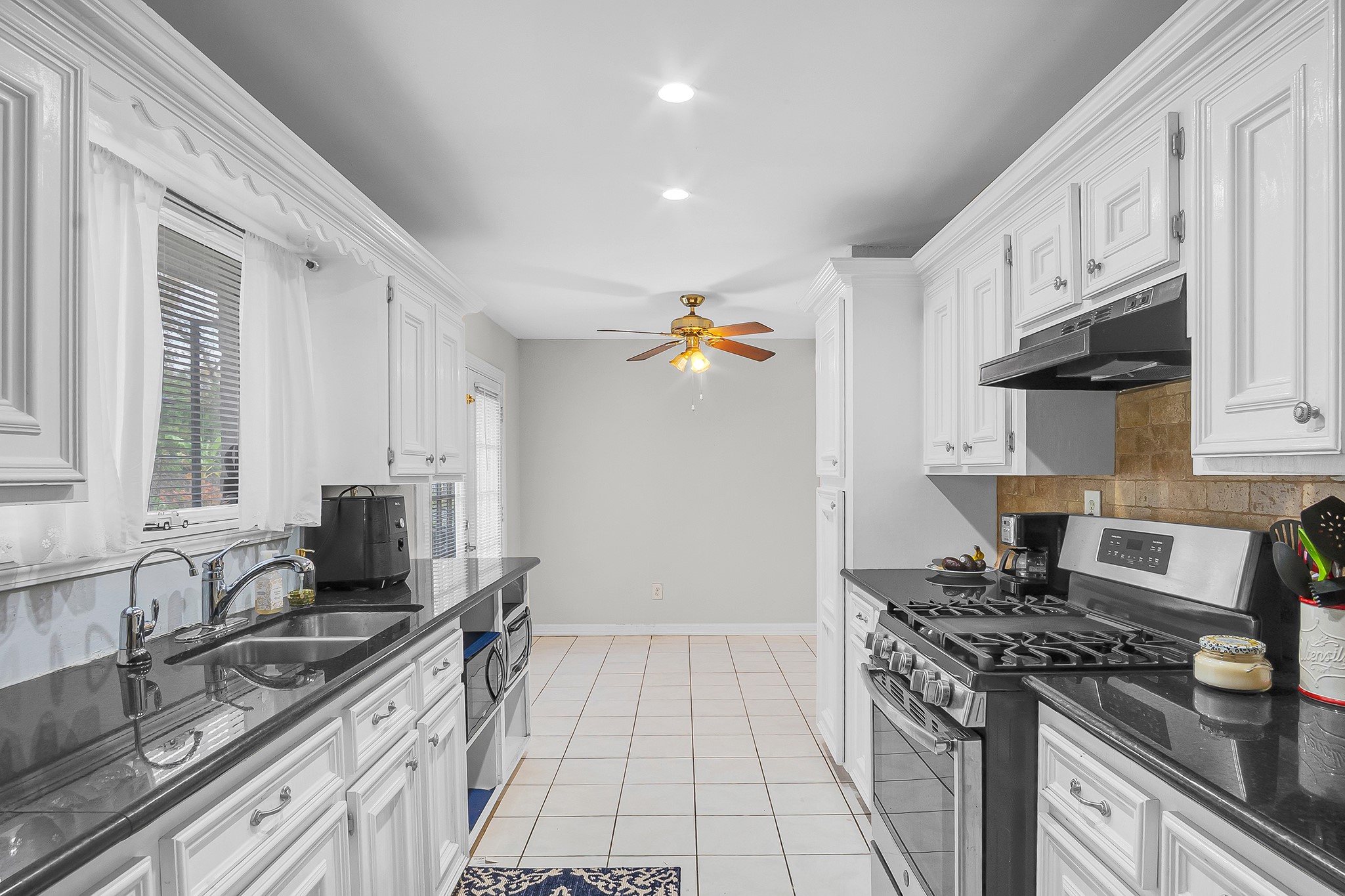 a kitchen with granite countertop a sink stove and refrigerator