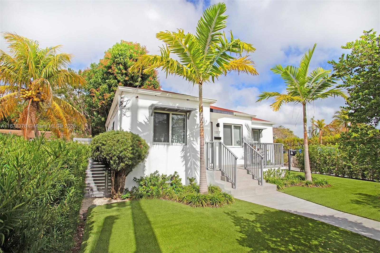a front view of a house with a yard and potted plants