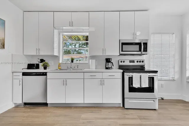 a kitchen with stainless steel appliances a stove a sink and white cabinets
