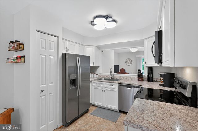 a kitchen with a refrigerator a sink and dishwasher with white cabinets