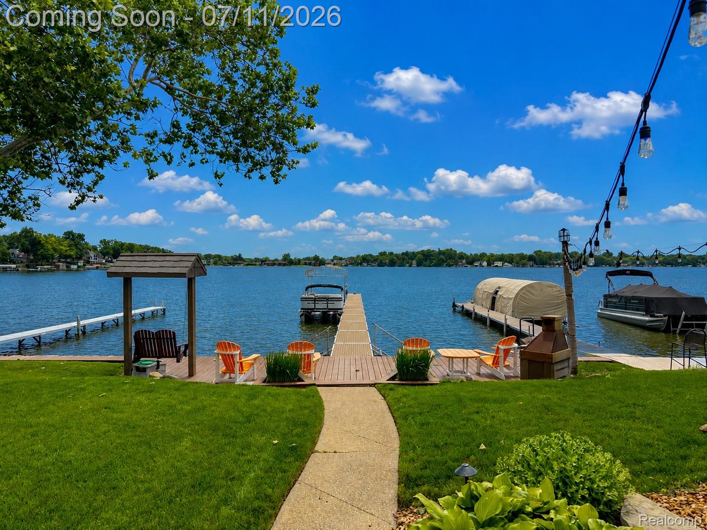 12033 Torrey Road Fenton, MI 48430 - Photo 5 of 51 Waterfront backyard featuring a manicured lawn, concrete pathway, and a wood-finish dock system