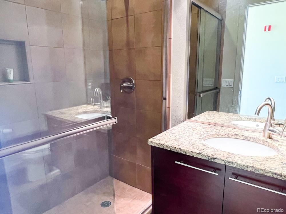 11570 Colony Row Broomfield, CO 80021 - Photo 13 of 24 a bathroom with a granite countertop sink a mirror and shower