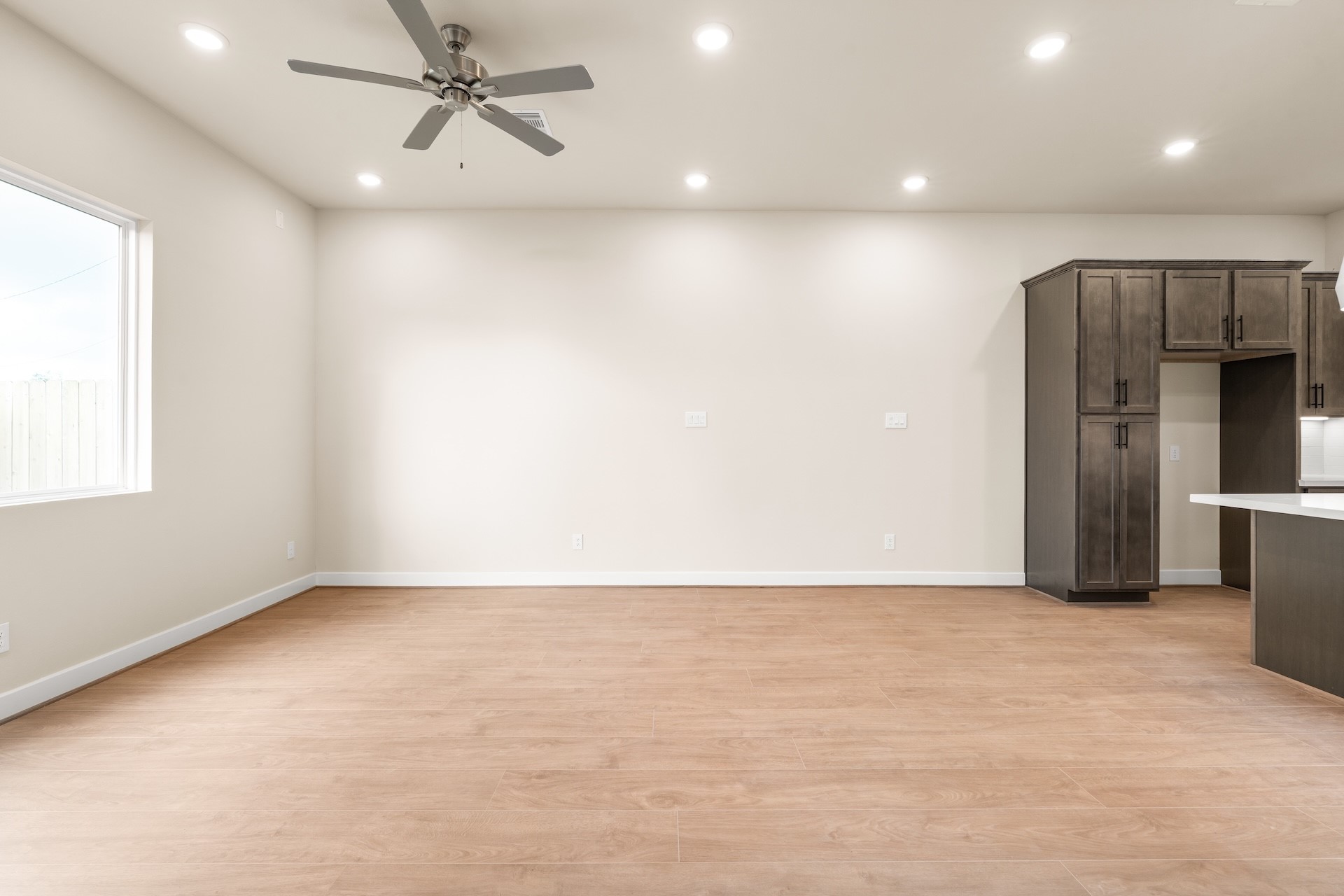6521 Rena Street Houston, TX 77092 - Photo 10 of 24 Light-filled open space — generous living area layout framed by side-yard windows, tall baseboards, and built-in kitchen cabinetry.