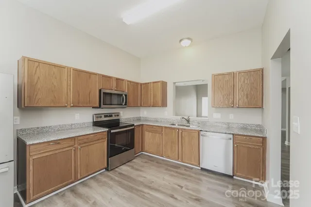 a kitchen with stainless steel appliances granite countertop a stove top oven a sink dishwasher and white cabinets with wooden floor