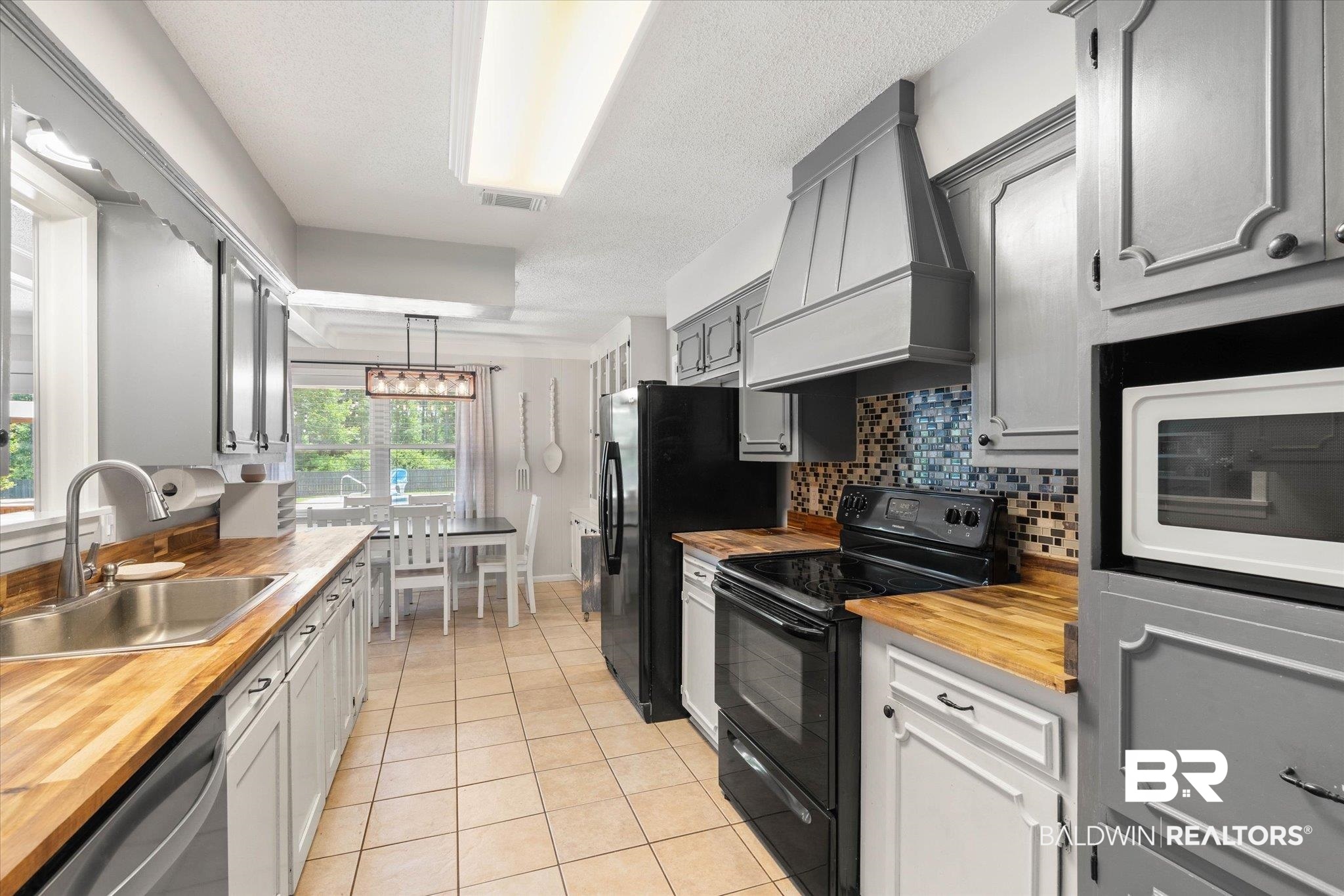 1025 Walter Smith Road Mobile, AL 36695 - Photo 5 of 46 Kitchen with wooden counters, black appliances, custom range hood, a sink, and light tile patterned floors