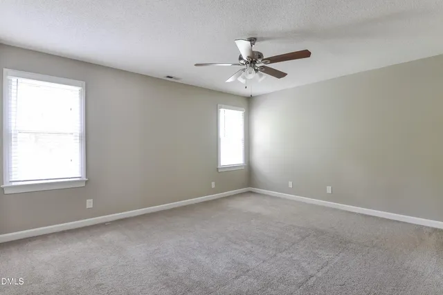 an empty room with windows and fan