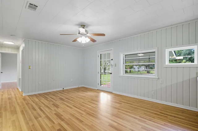 a view of a big room with wooden floor and a chandelier fan