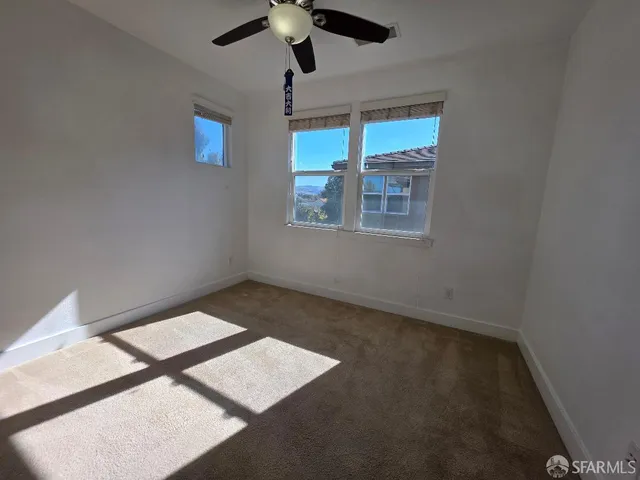 en empty room with windows and ceiling fan