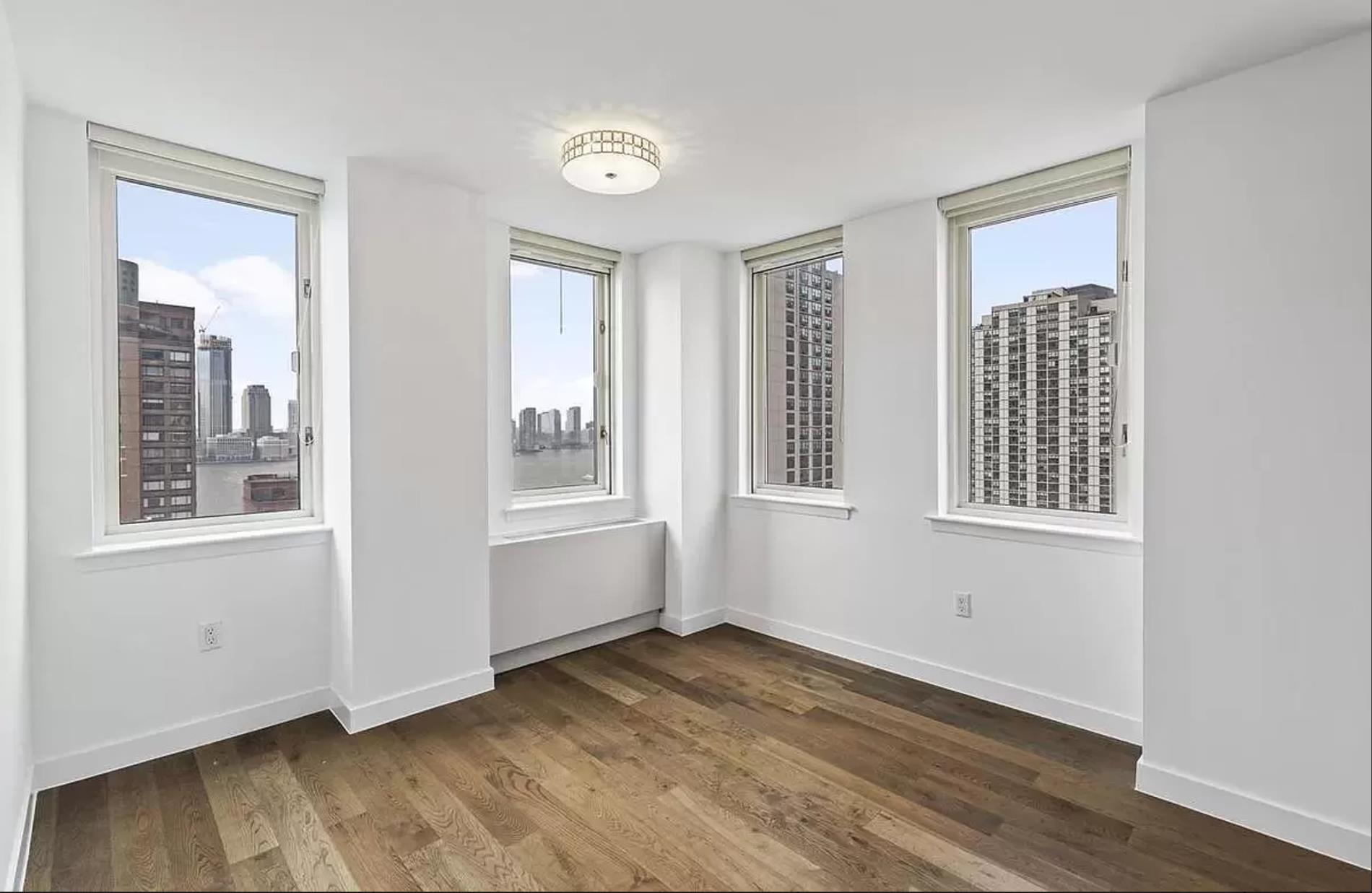 225 Rector Place, Unit 22H Manhattan, NY 10280 - Photo 2 of 13 a view of an empty room with wooden floor and a window