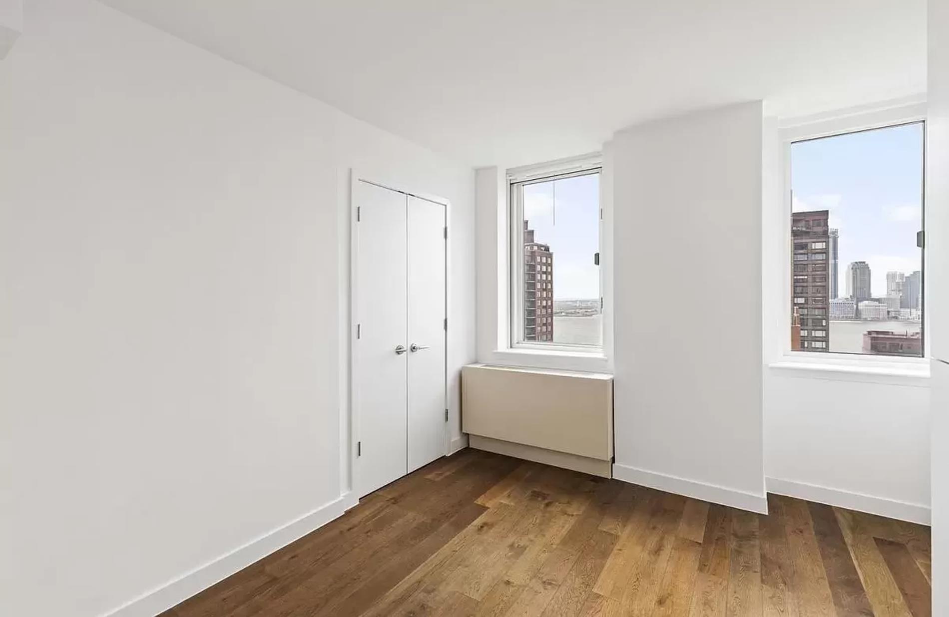 225 Rector Place, Unit 22H Manhattan, NY 10280 - Photo 4 of 13 a view of an empty room with wooden floor and a window