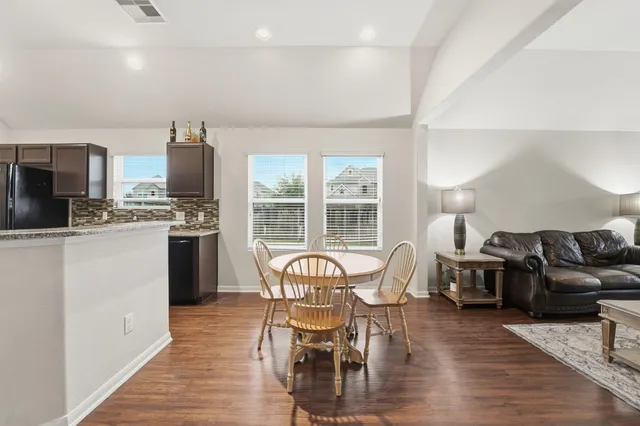 a living room with furniture a fireplace and a dining table with wooden floor