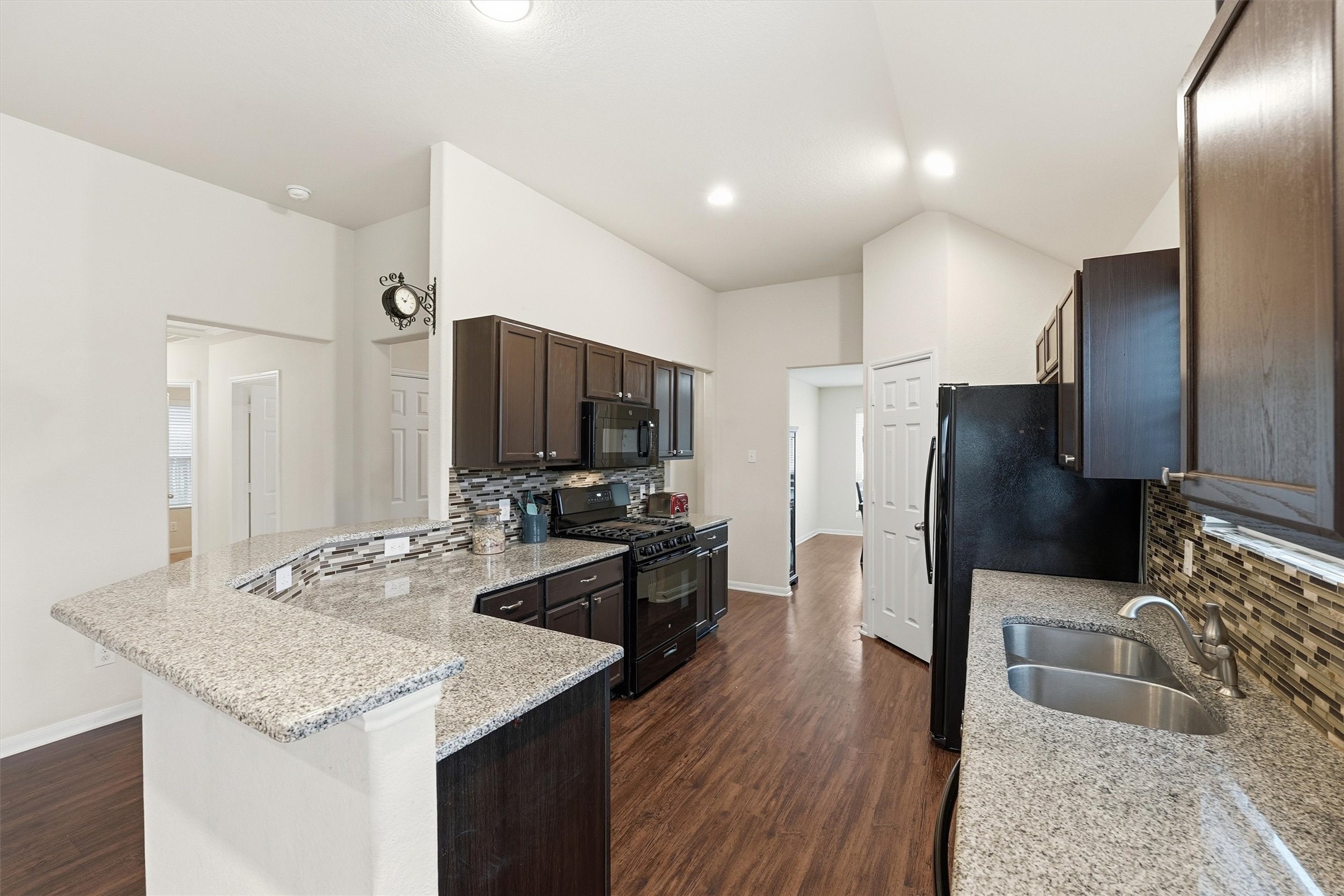2115 Pacific Loon Lane Conroe, TX 77385 - Photo 8 of 26 a kitchen with stainless steel appliances kitchen island granite countertop a refrigerator a stove and a sink