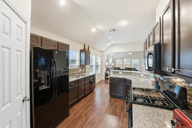 a kitchen with stainless steel appliances granite countertop a stove refrigerator and cabinets