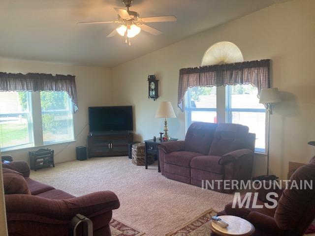 1095 County Road 70 Weiser, ID 83672 - Photo 13 of 44 Carpeted living area featuring vaulted ceilings, a ceiling fan, and multiple windows including an arched transom window