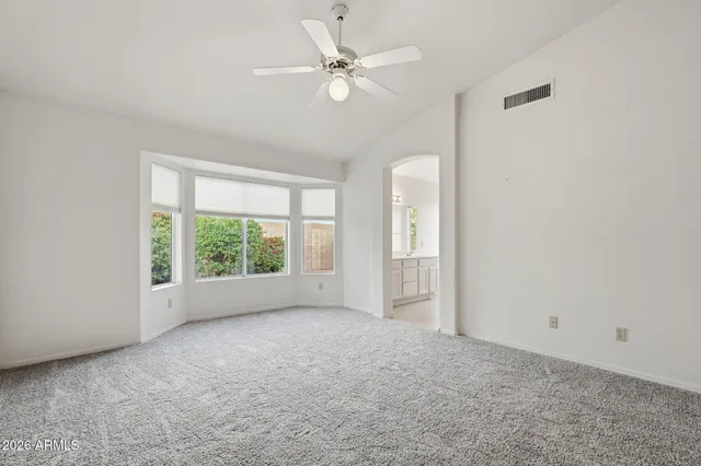 an empty room with windows and ceiling fan view