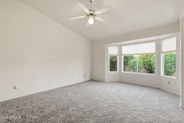 an empty room with windows and fan