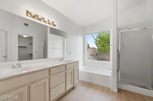 a spacious bathroom with a double vanity sink a large mirror a bathtub and next to a window