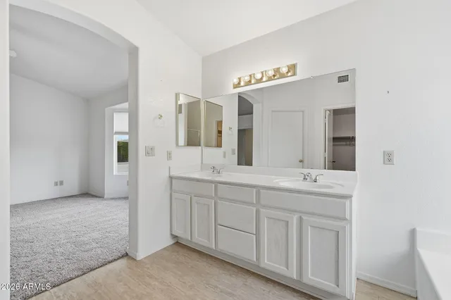 a spacious bathroom with a double vanity sink a mirror and a shower