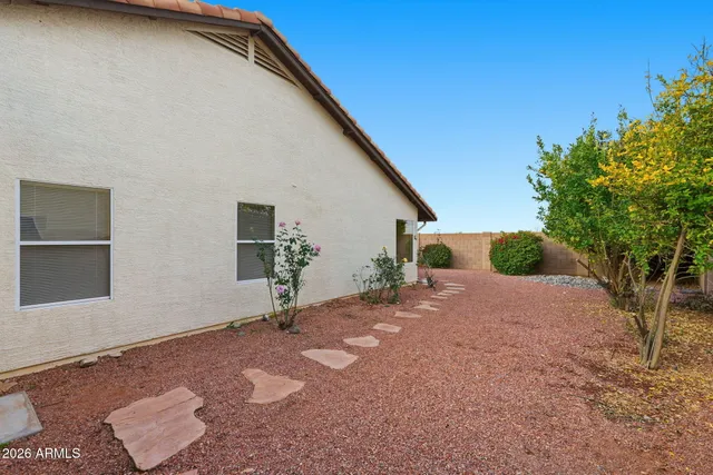 a backyard of a house with table and chairs under an umbrella