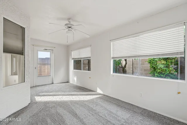 an empty room with windows and ceiling fan