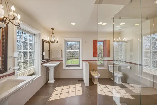 a bathroom with a tub sink toilet and large windows