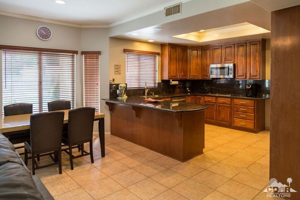 41310 Carlotta Drive Palm Desert, CA 92211 - Photo 17 of 32 a kitchen with stainless steel appliances granite countertop a stove a sink a counter space and dining table