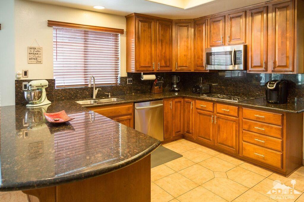 41310 Carlotta Drive Palm Desert, CA 92211 - Photo 3 of 32 a kitchen with granite countertop wooden cabinets a sink and a stove