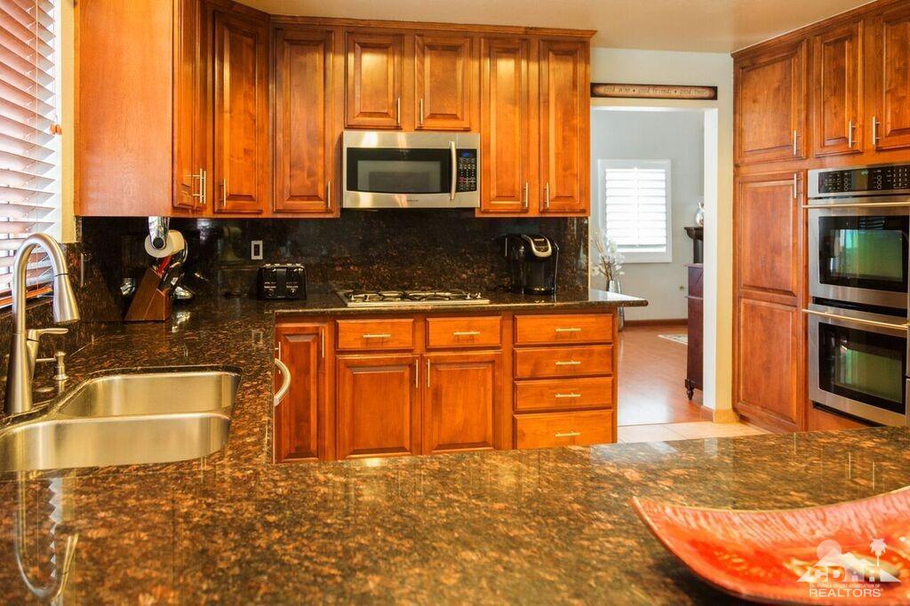 41310 Carlotta Drive Palm Desert, CA 92211 - Photo 7 of 32 a kitchen with granite countertop a stove a sink and a microwave