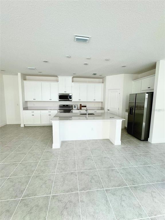 4826 Prairie Preserve Run St. Cloud, FL 34772 - Photo 6 of 44 a large white kitchen with stainless steel appliances granite countertop a stove a sink a microwave and a refrigerator