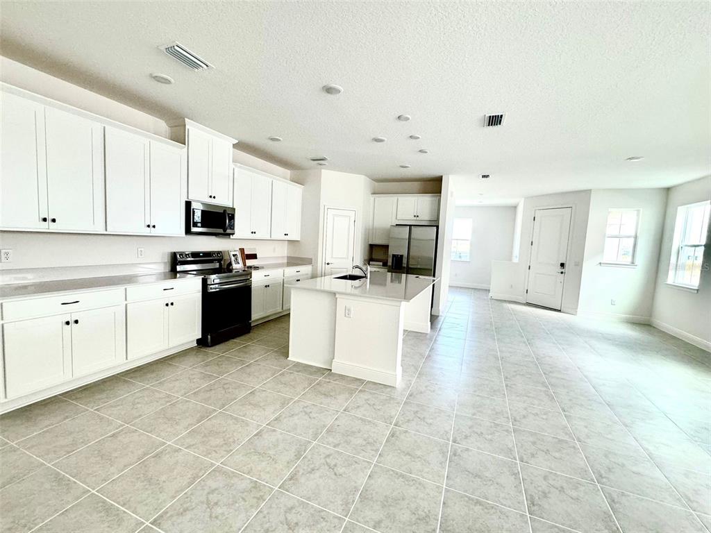 4826 Prairie Preserve Run St. Cloud, FL 34772 - Photo 7 of 44 a large white kitchen with cabinets and stainless steel appliances