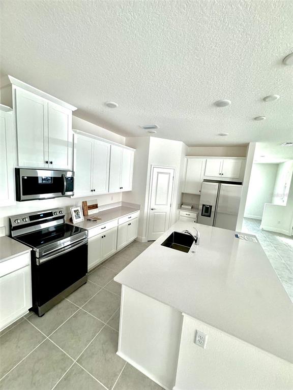 4826 Prairie Preserve Run St. Cloud, FL 34772 - Photo 8 of 44 a kitchen with stainless steel appliances a stove a sink a microwave and cabinets
