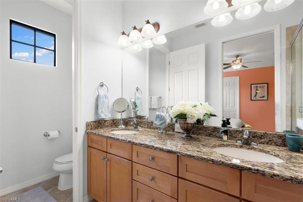 8985 Cambria Circle, Unit 211 Naples, FL 34113 - Photo 17 of 41 a bathroom with a granite countertop sink a toilet and a mirror