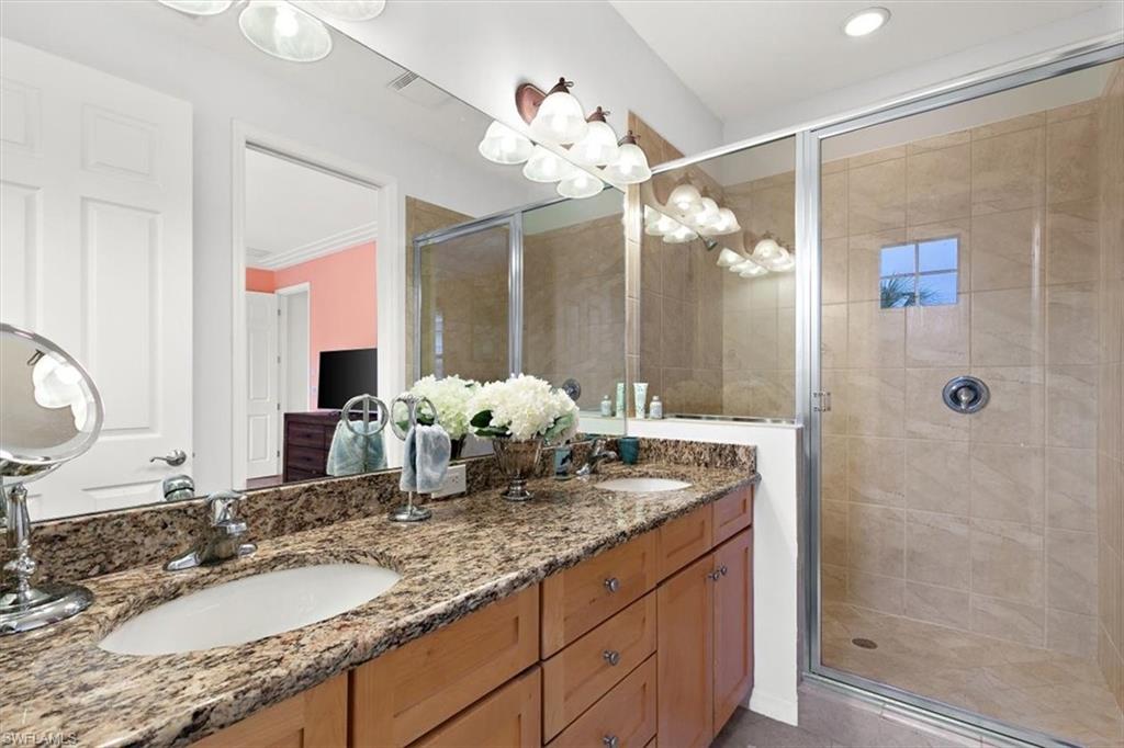 8985 Cambria Circle, Unit 211 Naples, FL 34113 - Photo 18 of 41 a bathroom with a granite countertop sink a large mirror and a shower
