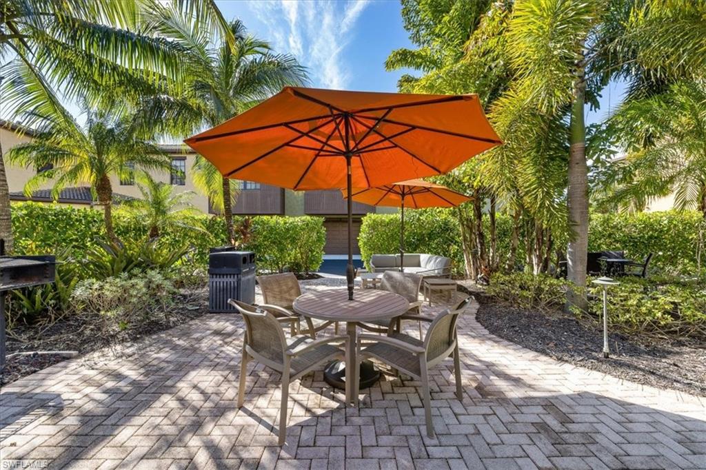 8985 Cambria Circle, Unit 211 Naples, FL 34113 - Photo 39 of 41 a view of patio with chairs and table under an umbrella