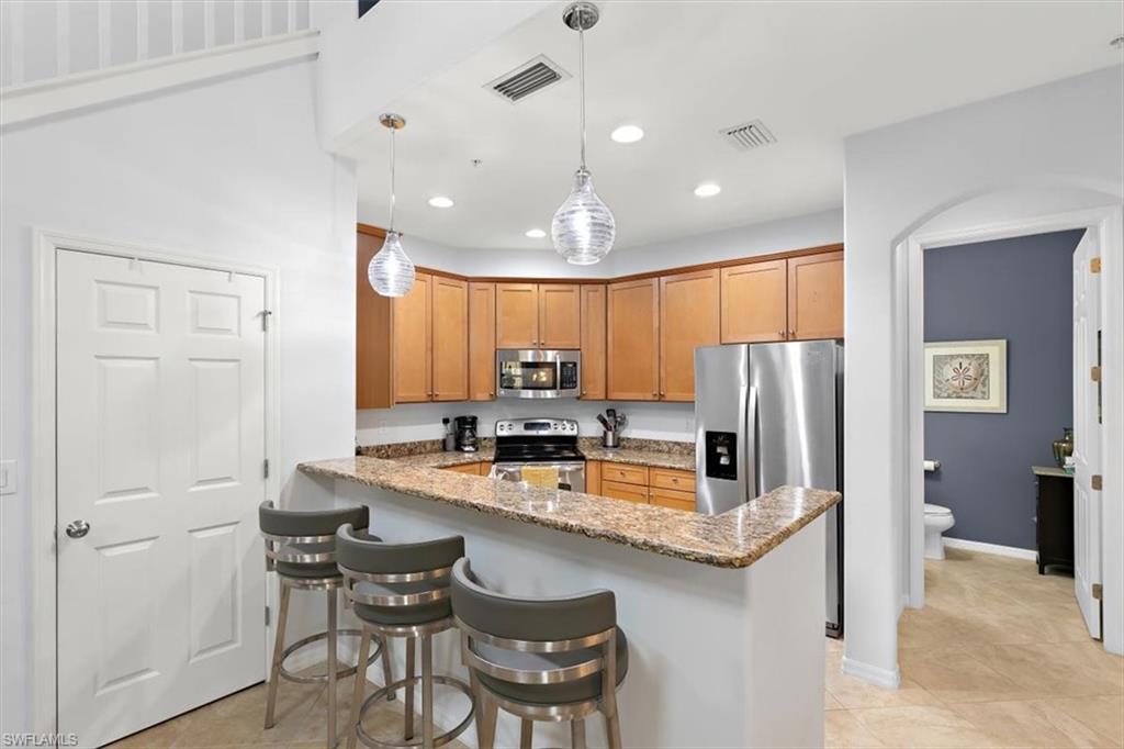 8985 Cambria Circle, Unit 211 Naples, FL 34113 - Photo 7 of 41 a kitchen with refrigerator a sink and chairs