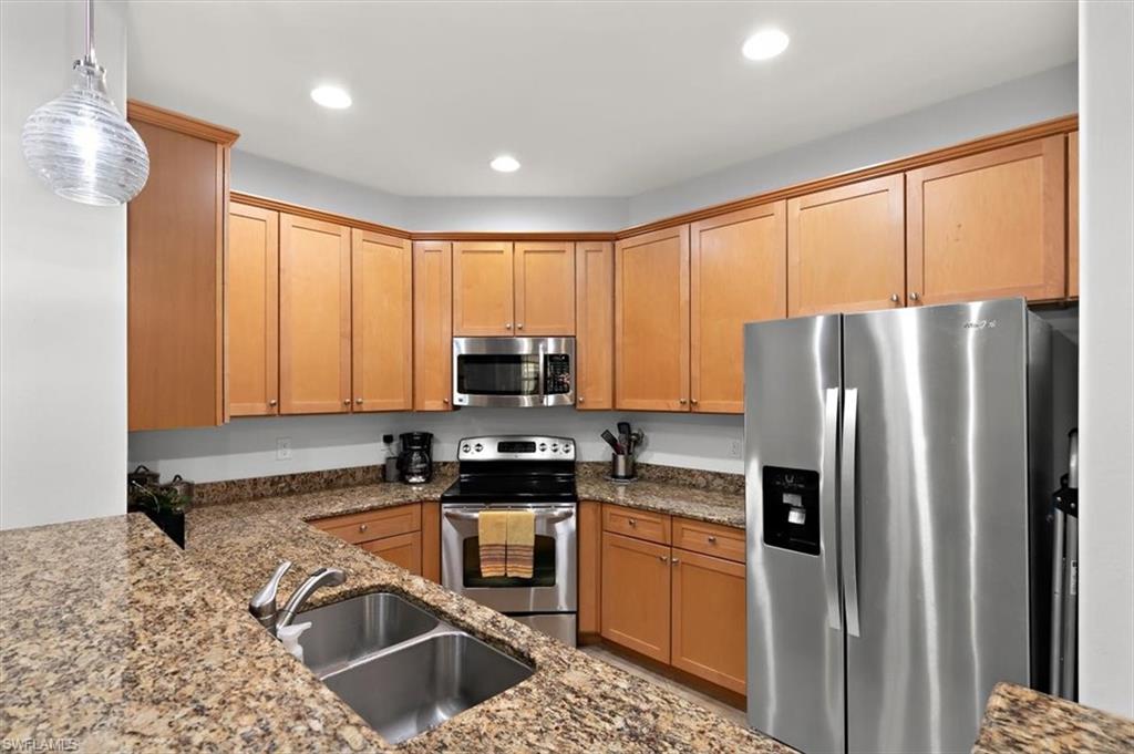8985 Cambria Circle, Unit 211 Naples, FL 34113 - Photo 8 of 41 a kitchen with kitchen island granite countertop a refrigerator stove top oven and sink