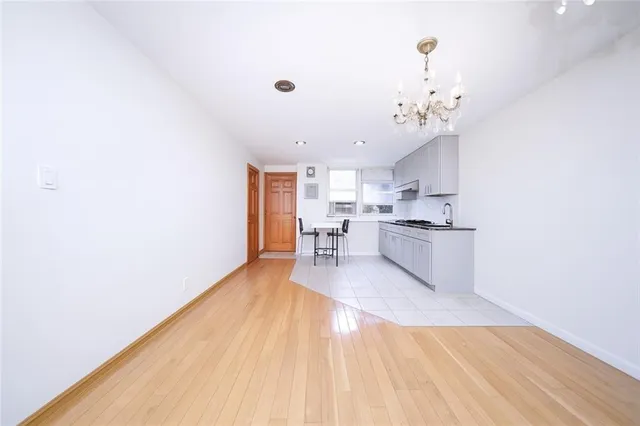 a view of a kitchen with kitchen island a sink wooden floor and stainless steel appliances