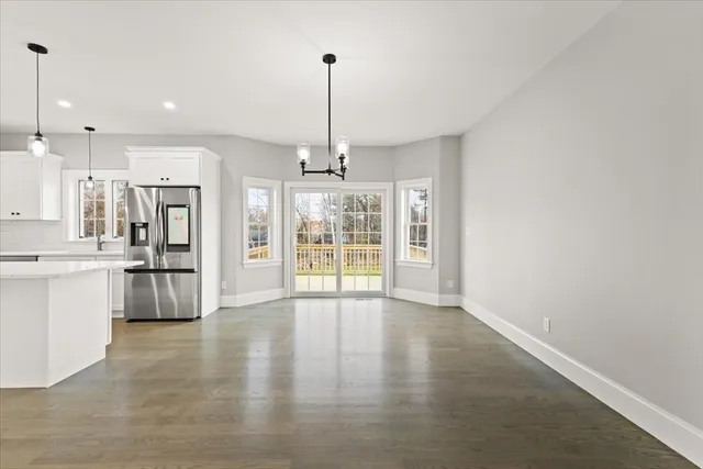 a view of an empty room with kitchen and window