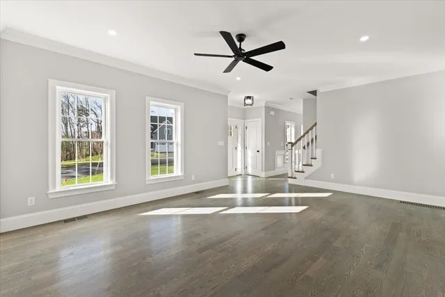 a view of empty room with wooden floor and fan