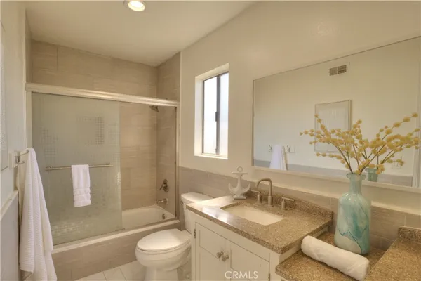 a bathroom with a granite countertop sink a toilet and shower