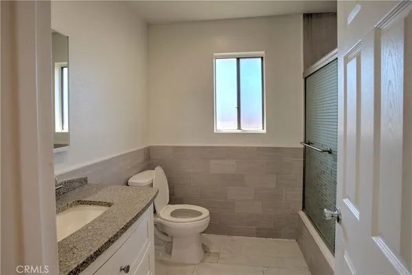 a bathroom with a granite countertop toilet a sink and a mirror
