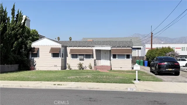 a view of a white house with a yard and a car parked on road