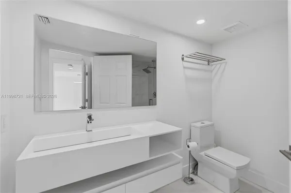 a bathroom with a toilet a sink a mirror and vanity